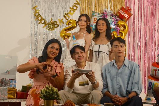 A group of friends enjoying a birthday party with decorations and cake in Jakarta.