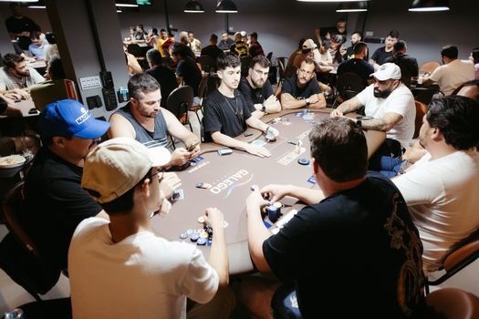 A group of adult men engage in a lively poker game at a vibrant casino setting.