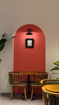 Inviting café nook with wooden chairs and table against a vibrant red background.