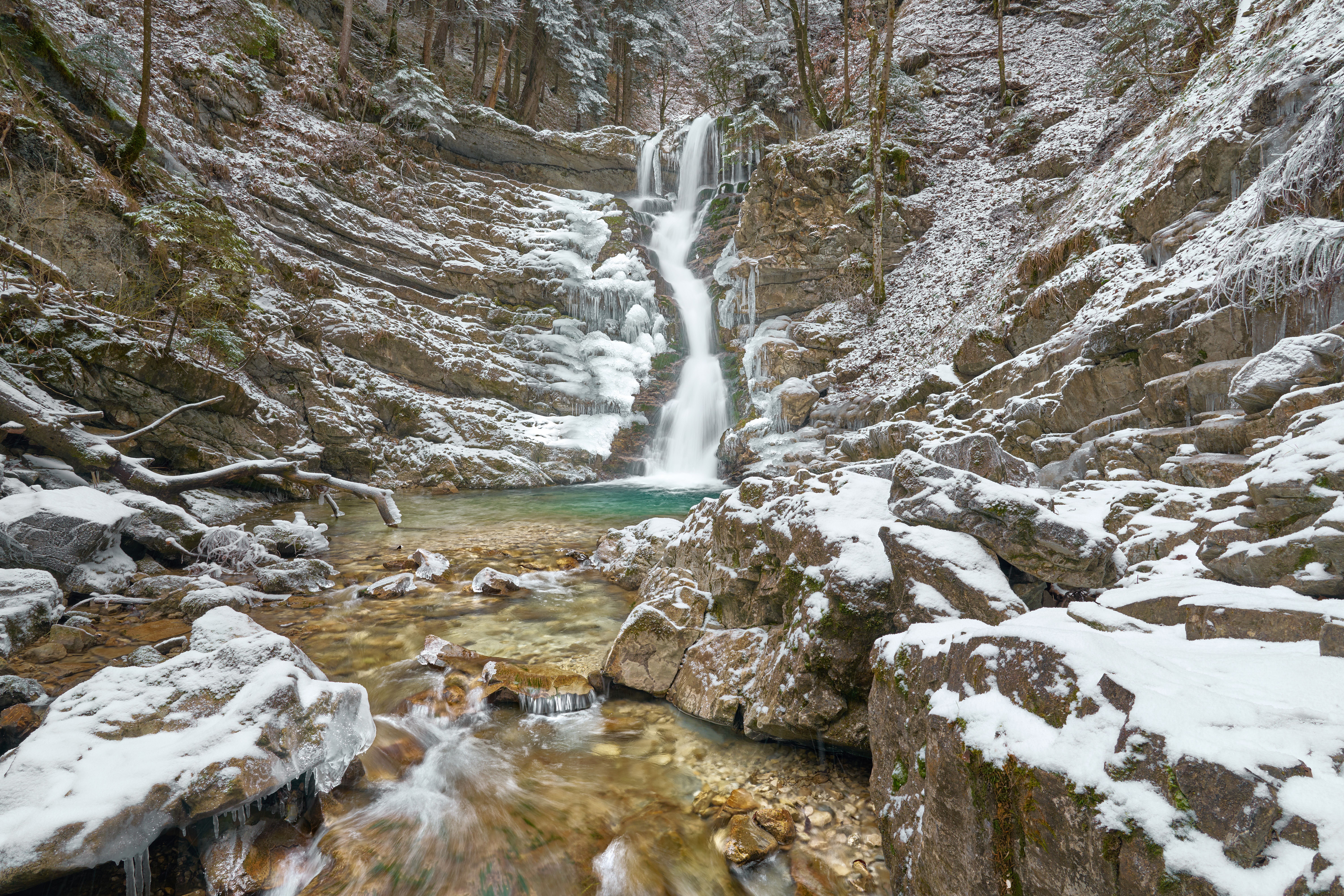 A picturesque frozen waterfall in a snowy forest in Bavaria, Germany.