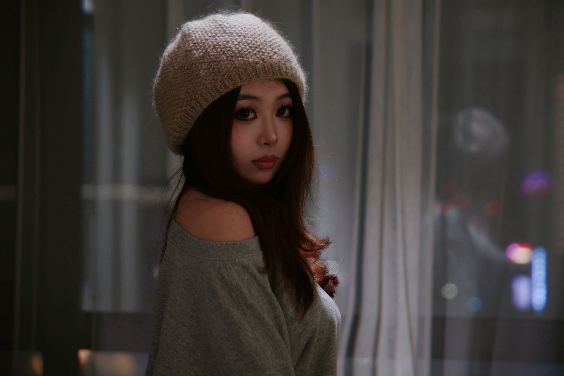 Indoor portrait of a young woman in a cozy beanie, exuding warmth and style.