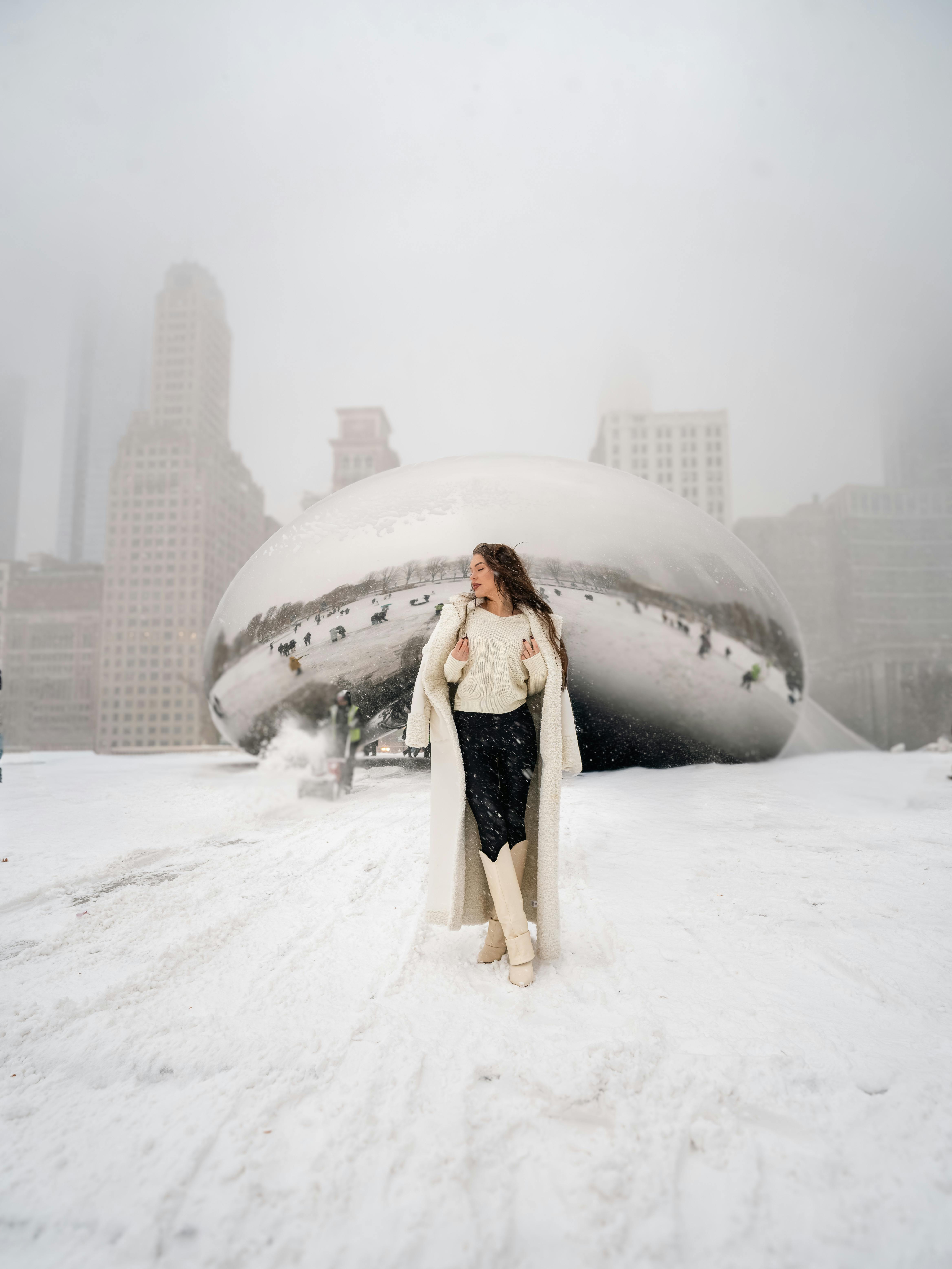 Kostnadsfria En kvinna i vinterkläder står framför Chicagos Cloud Gate under en snöstorm. Stock foto