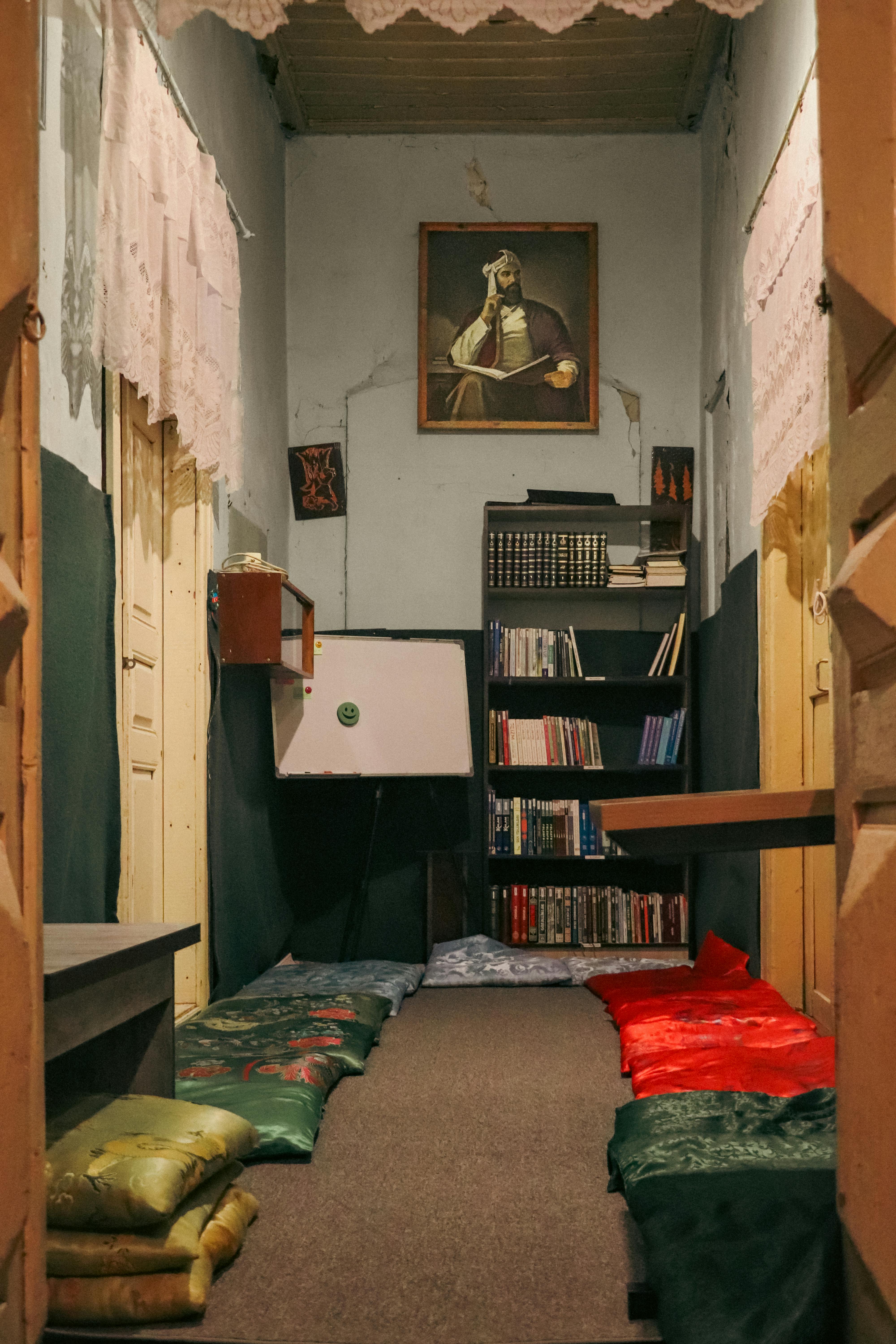 Gratuit Un colț de lectură cald și primitor, cu perne, bibliotecă și opere de artă. Fotografie de stoc