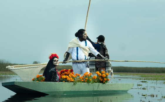Traditional Dia de los Muertos celebration with people in costume on a boat.