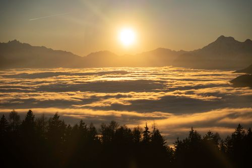 Free Golden sunset illuminating clouds over Crans-Montana, Switzerland with alpine silhouettes. Stock Photo
