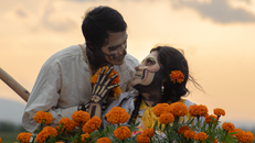 A couple celebrating Dia de los Muertos with traditional skull face paint and marigolds.