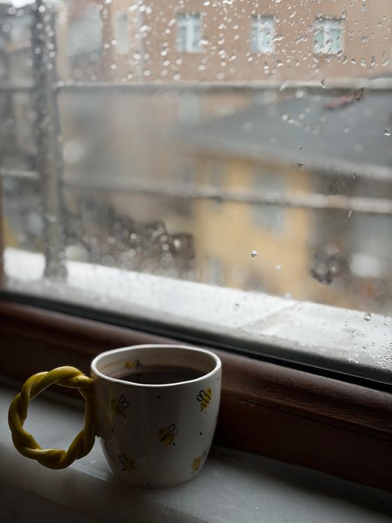 Free Warm coffee mug on a windowsill during a rainy day. Cozy and calm atmosphere. Stock Photo