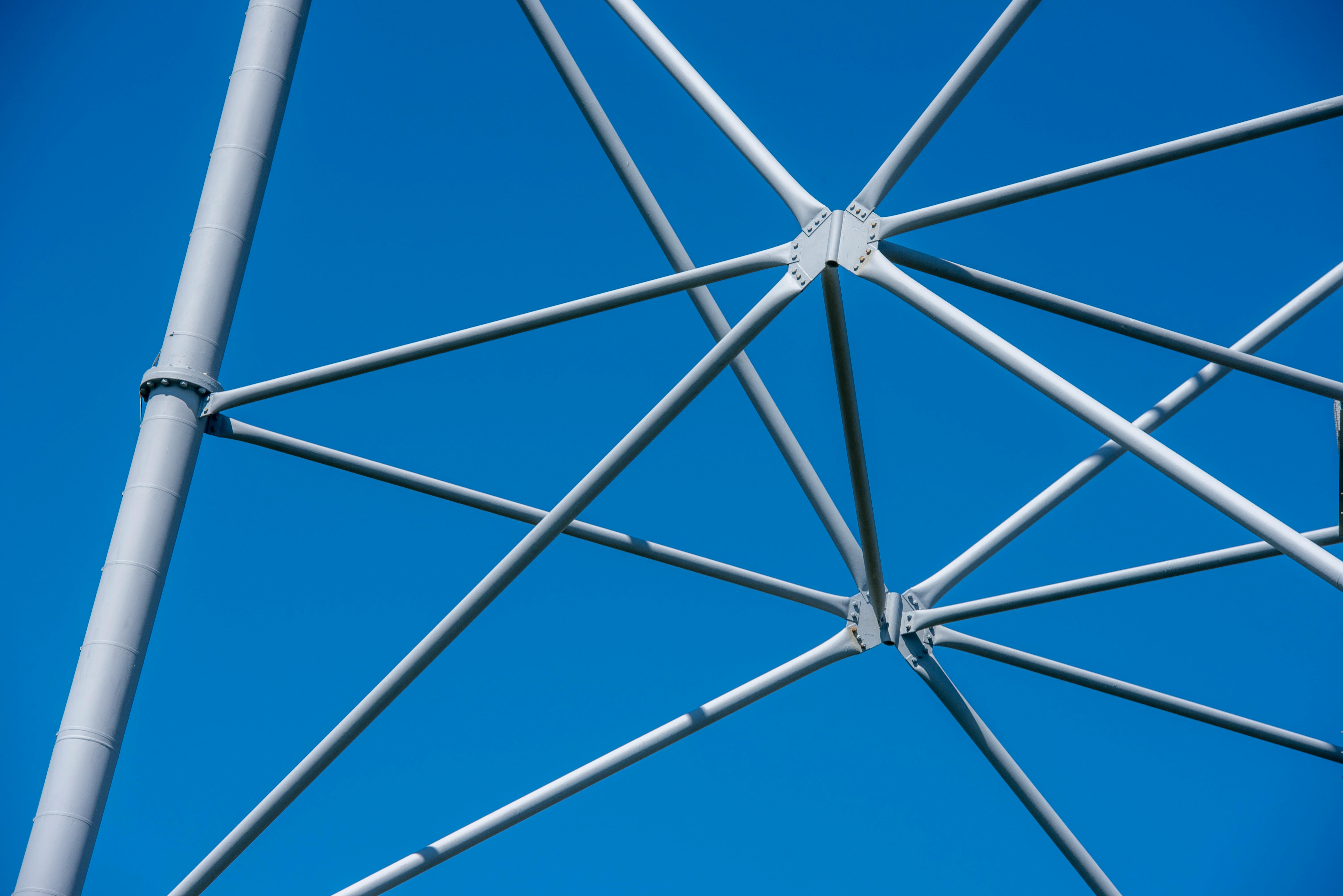 Free A detailed view of a modern steel mast structure set against a clear blue sky, showcasing engineering elements. Stock Photo