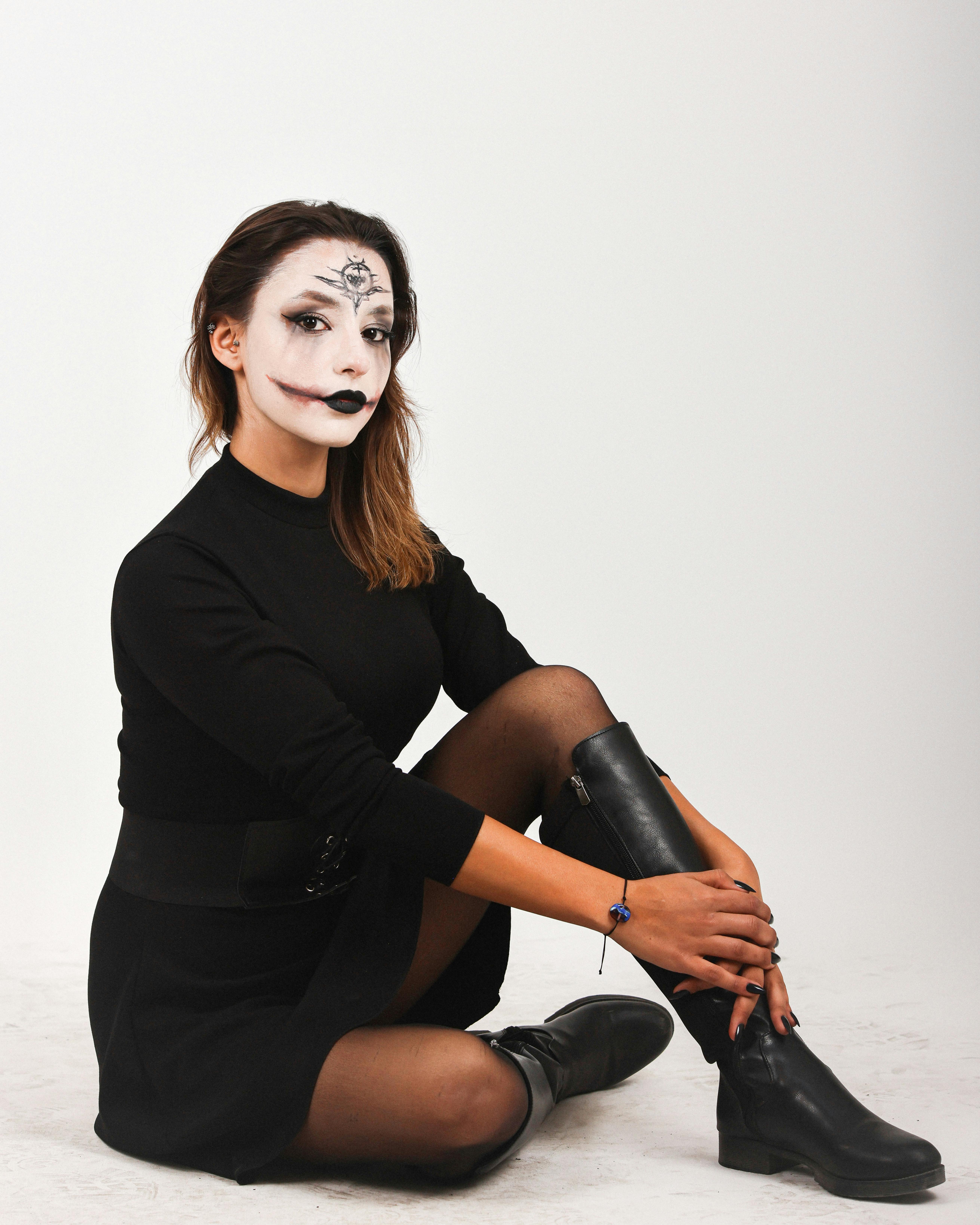 De franc Una dona jove amb maquillatge gòtic i roba negra posa sobre un fons blanc, adoptant un estil artístic dramàtic. Foto d'estoc