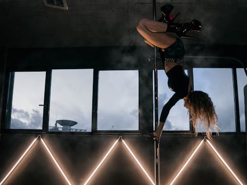 A woman doing a pole dance in front of a window