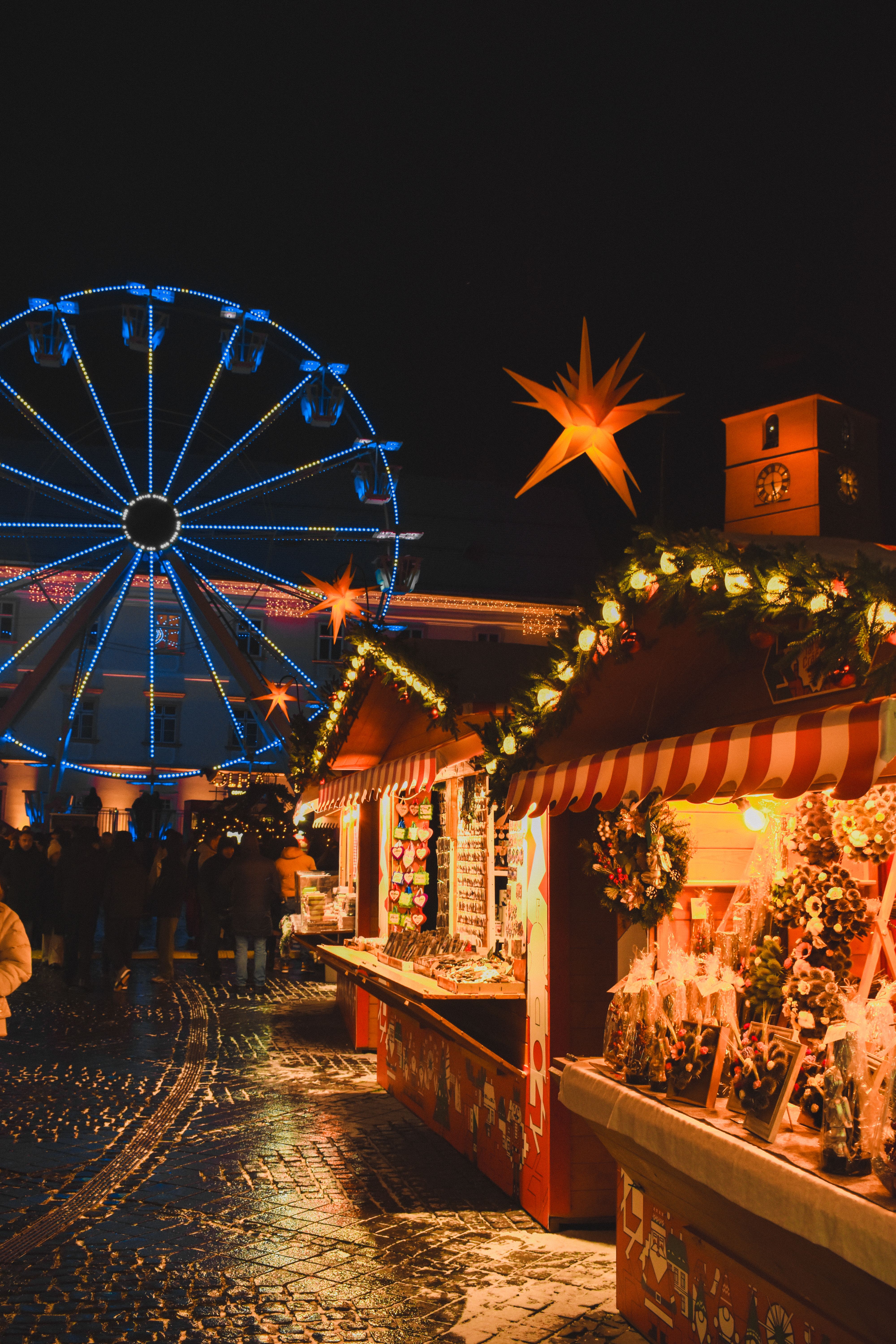 European Christmas market at night with lights and a ferris wheel