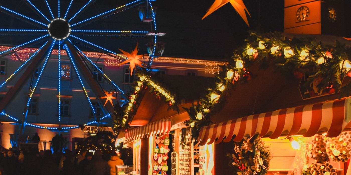 European Christmas market at night with lights and a ferris wheel