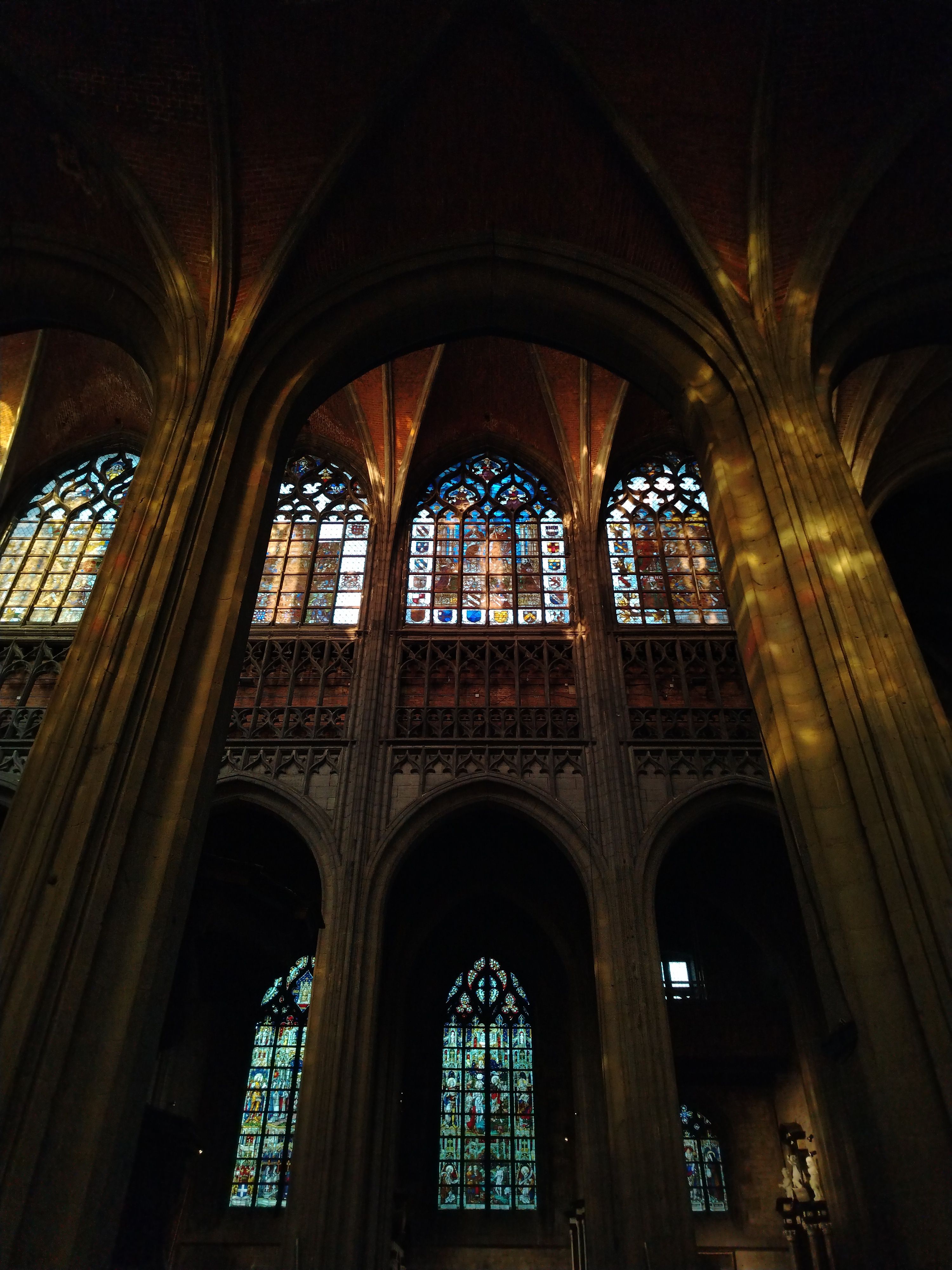 Interior view of a Gothic cathedral in Mons, Belgium showcasing stunning stained glass windows.