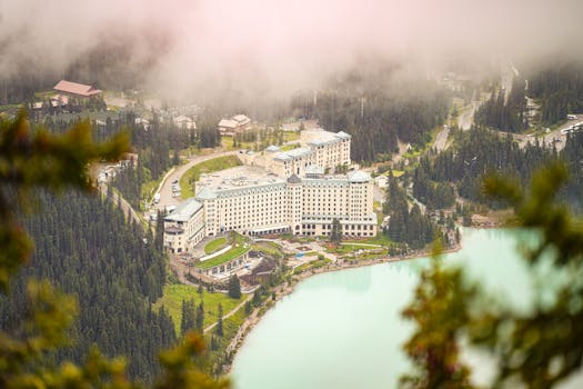 Aerial view of a grand hotel surrounded by forested mountains and turquoise lake at Lake Louise, Alberta, Canada.