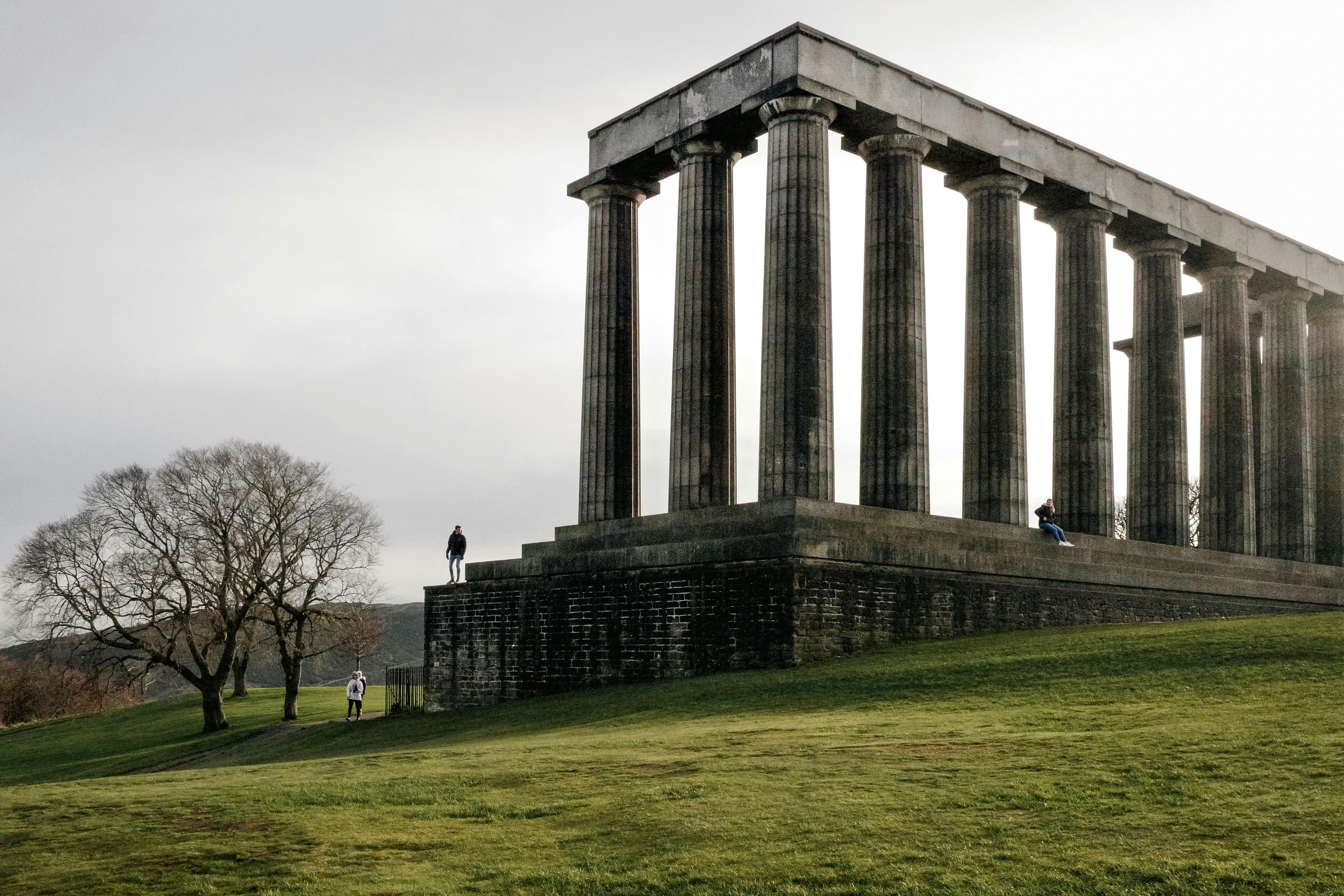 Dramatic view of the historic Greek-style columns at Calton Hill, Edinburgh, Scotland during daytime.
