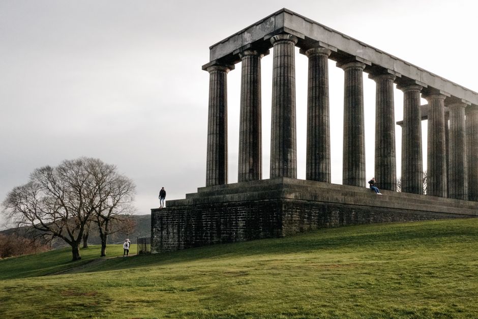 Dramatic view of the historic Greek-style columns at Calton Hill, Edinburgh, Scotland during daytime.