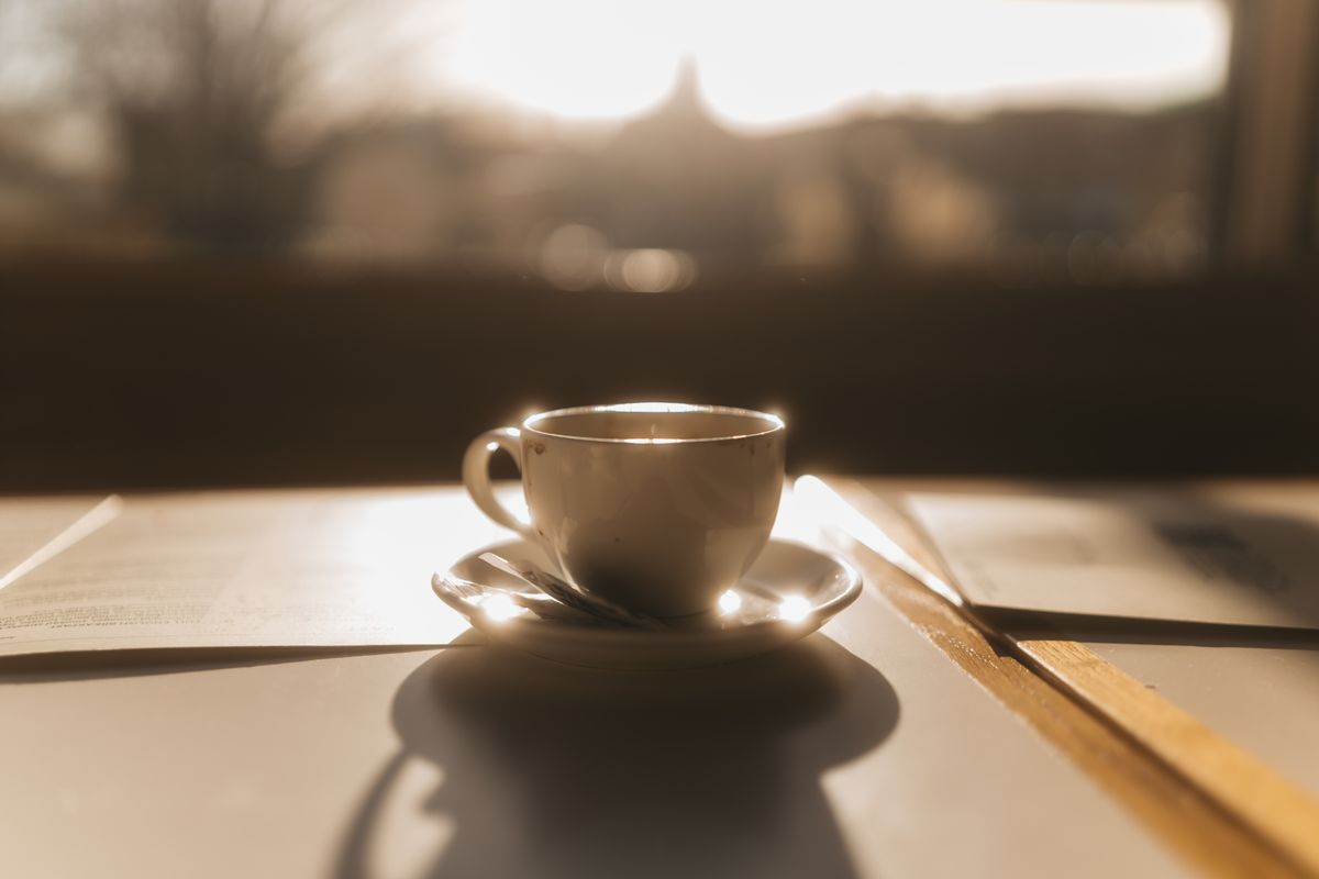 A cup of coffee on a counter in the first light of the morning.
