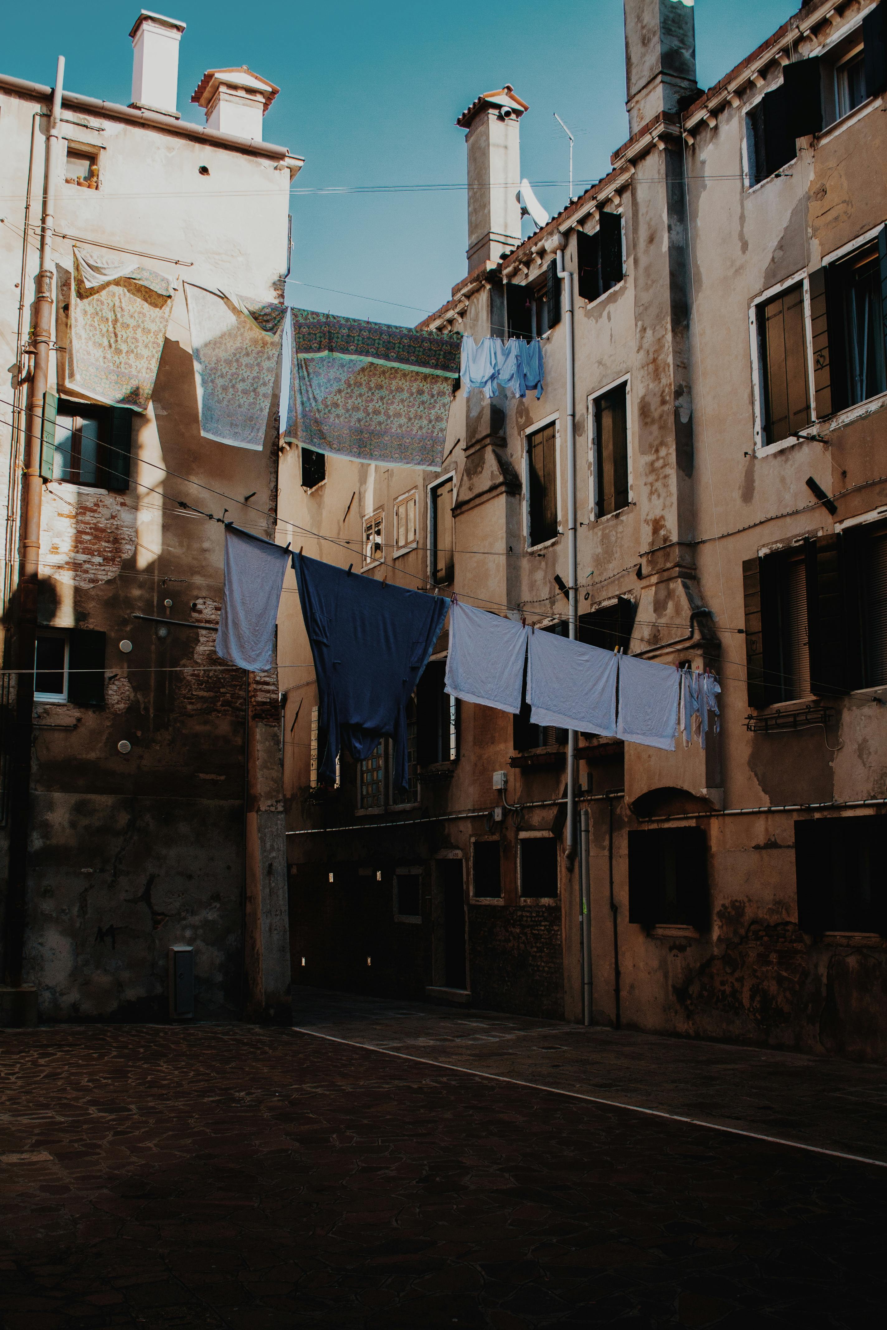 Narrow street with shabby walls of aged apartment buildings with clothes drying on ropes
