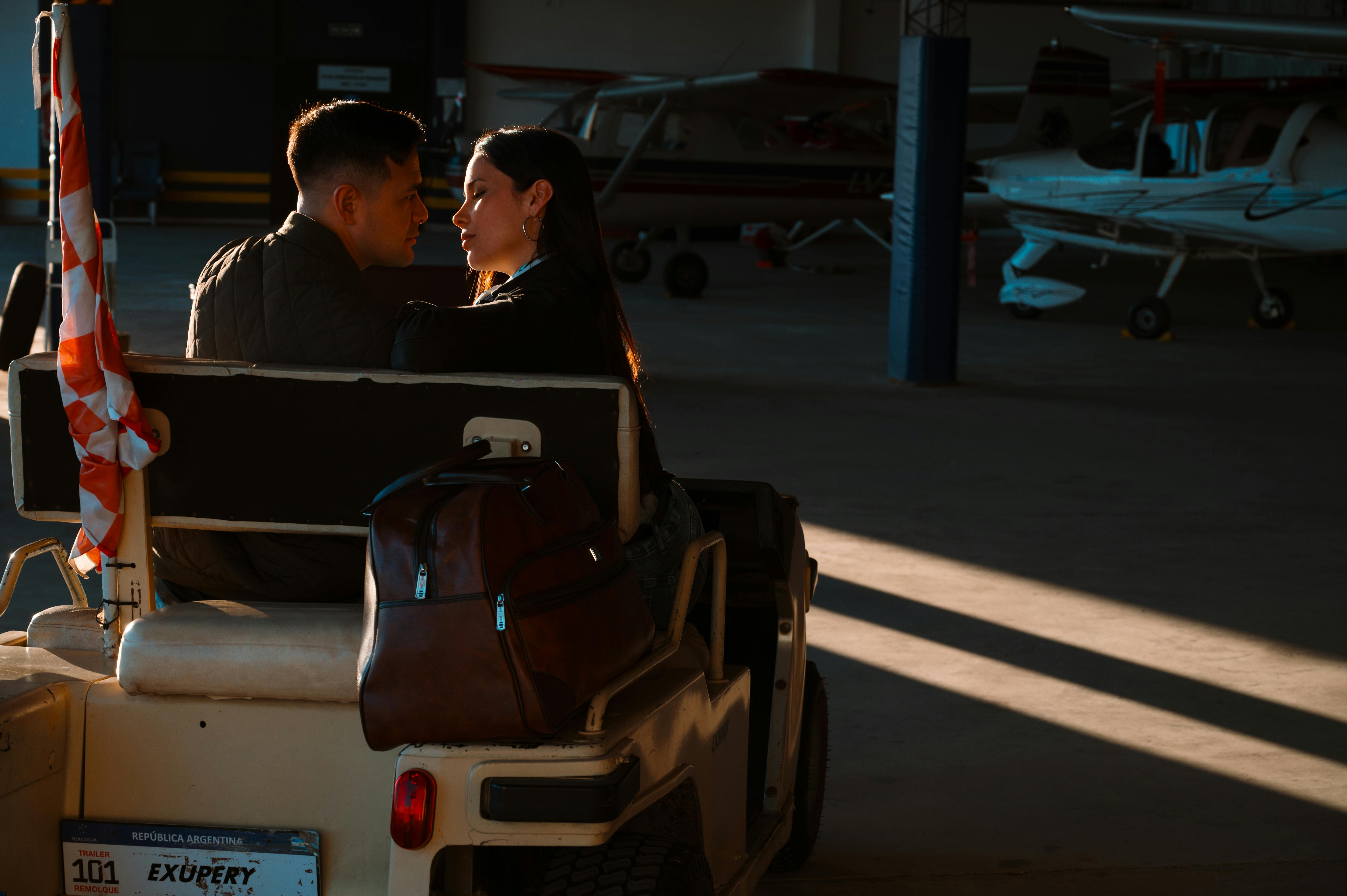 Zadarmo Pár zdieľa chvíľku v hangári lietadiel vedľa malých lietadiel pri západe slnka. Fotka z fotobanky