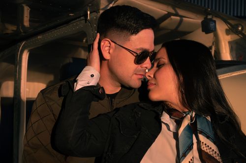 Free A couple shares a tender moment by an airplane, bathed in sunset light. Stock Photo