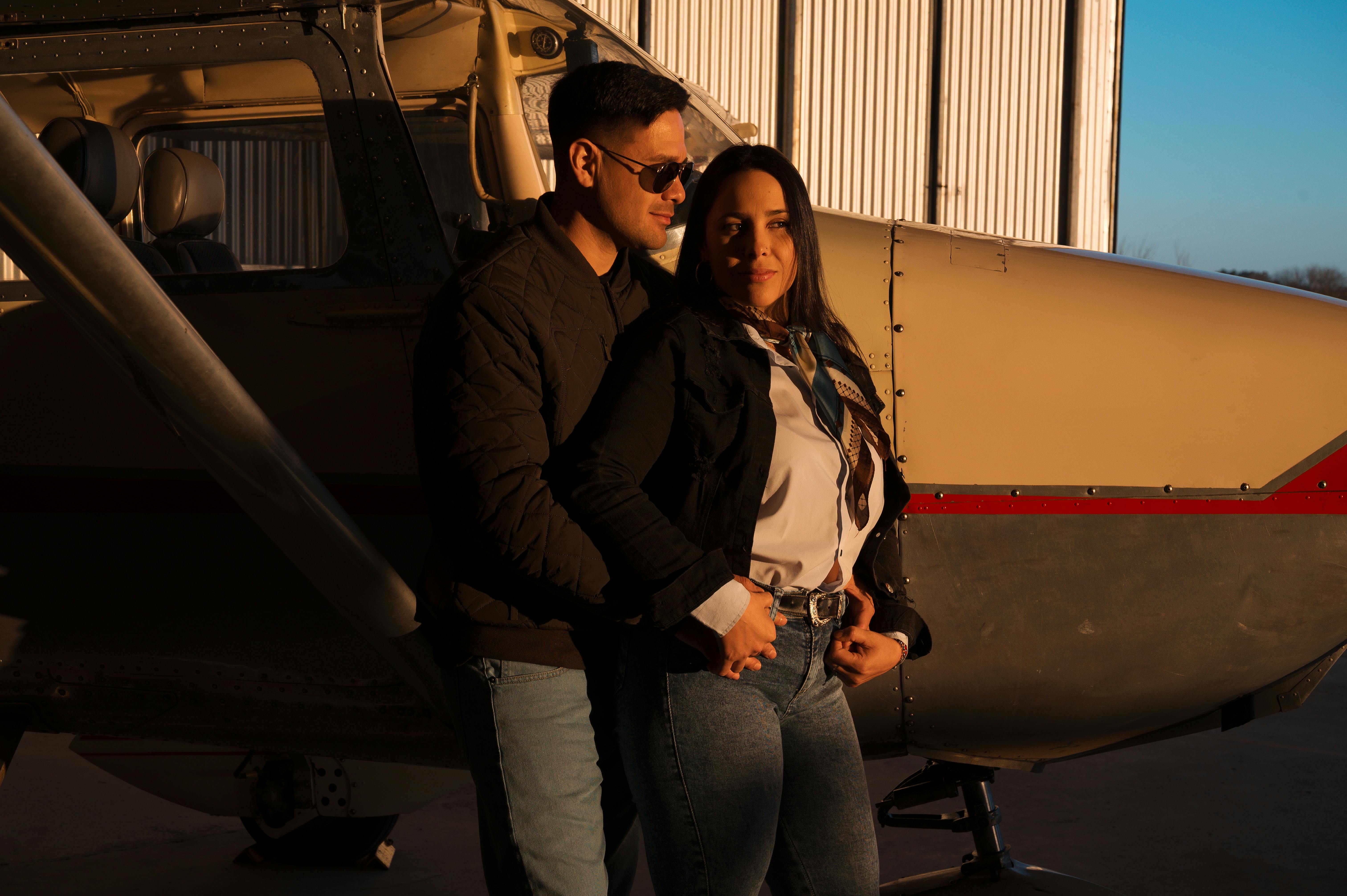 Zadarmo Pár sa vrúcne objíma vedľa lietadla v hangári počas západu slnka. Fotka z fotobanky