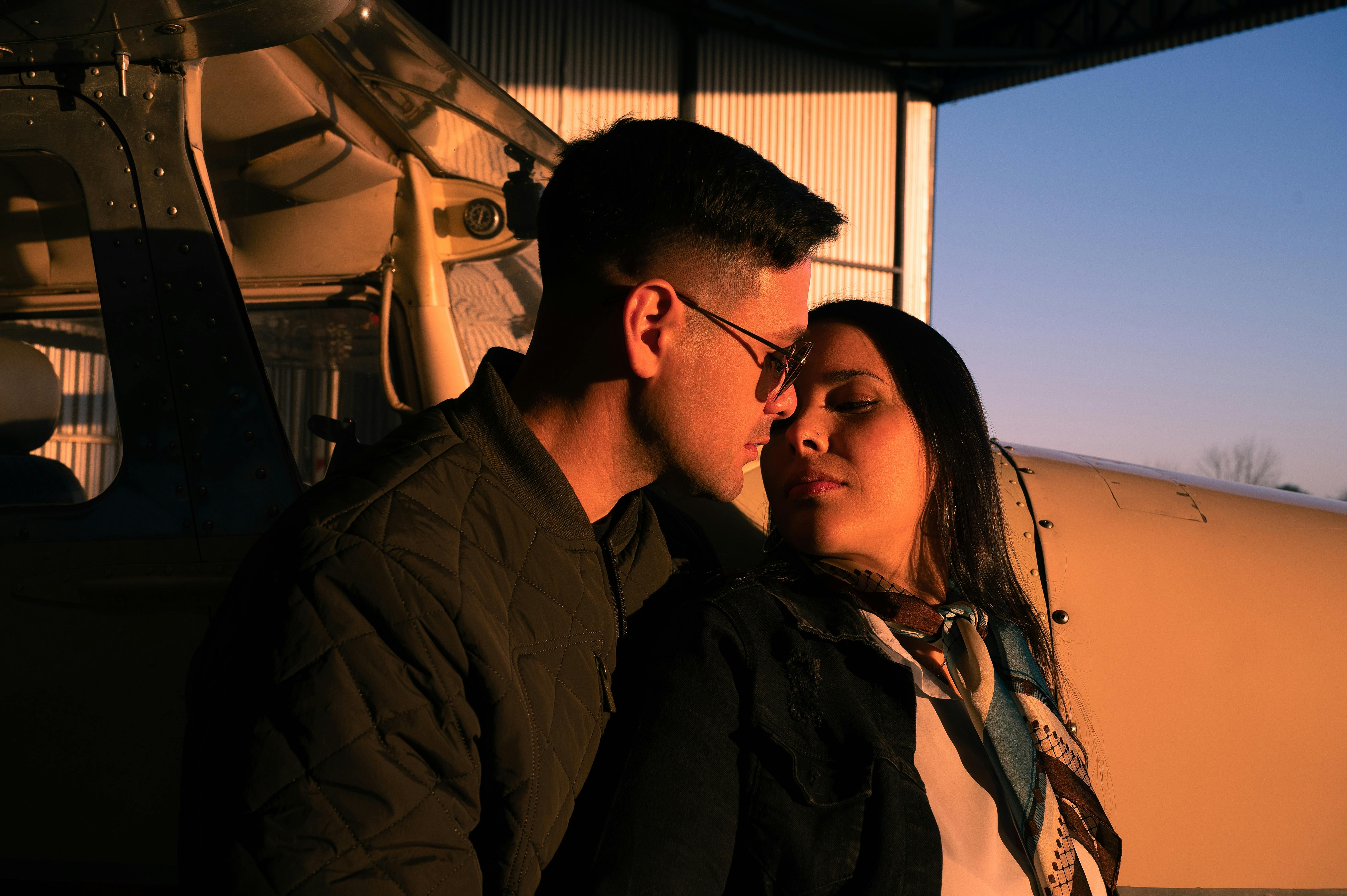Zadarmo Pár zdieľa nežnú chvíľku pri súkromnom lietadle v hangári. Fotka z fotobanky