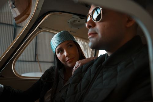 Free A couple in sunglasses and scarf sitting inside an airplane, preparing for an adventure. Stock Photo