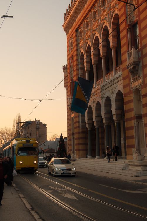 Free Stunning sunset view of Sarajevo City Hall with tram and street scenery. Stock Photo