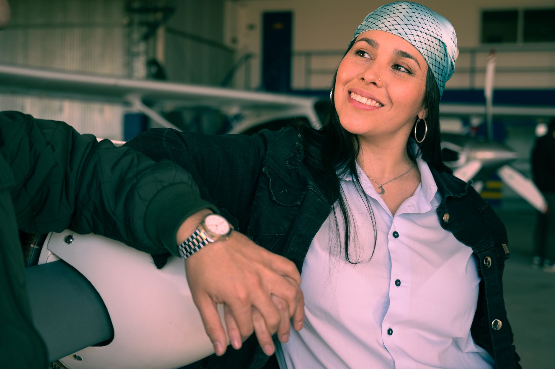 Woman smiling indoors at an airplane hangar, embracing friendship and travel.