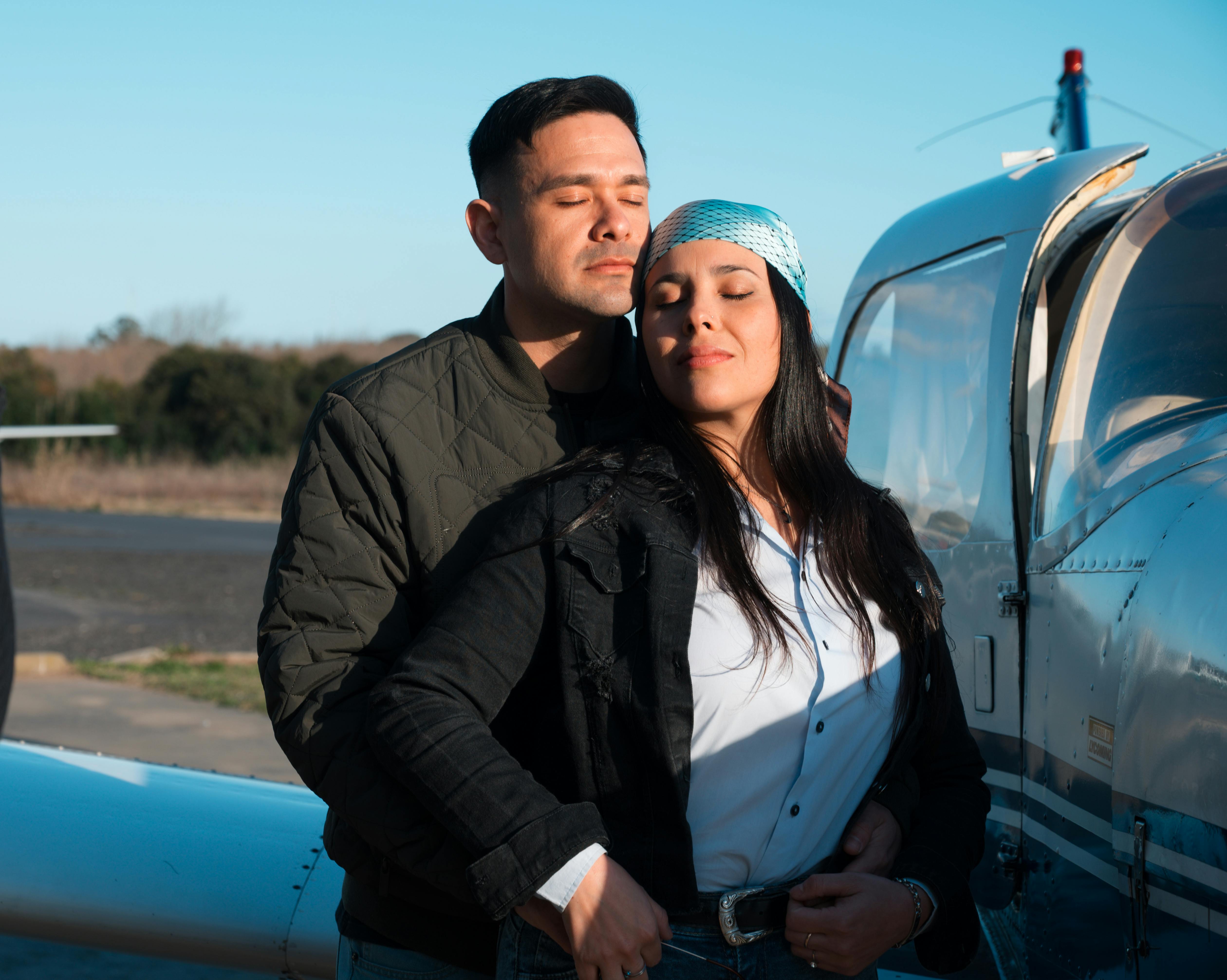 Zadarmo Zamilovaný pár objímajúci sa vedľa súkromného lietadla pod jasnou oblohou. Fotka z fotobanky