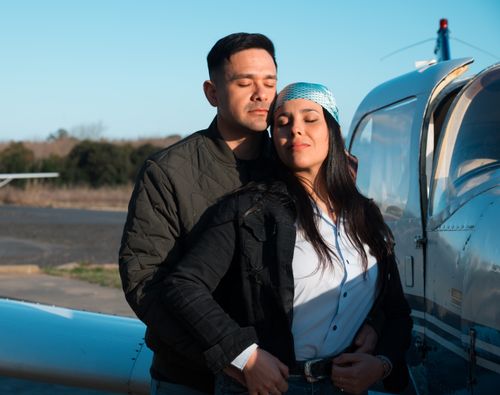 Free A couple enjoys a serene moment embracing beside a parked airplane outdoors. Stock Photo