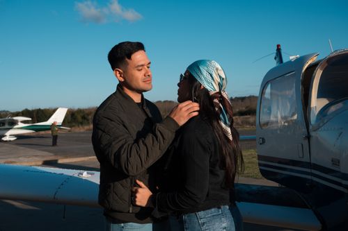 Free A couple shares a tender moment by a small airplane on a sunny day. Stock Photo