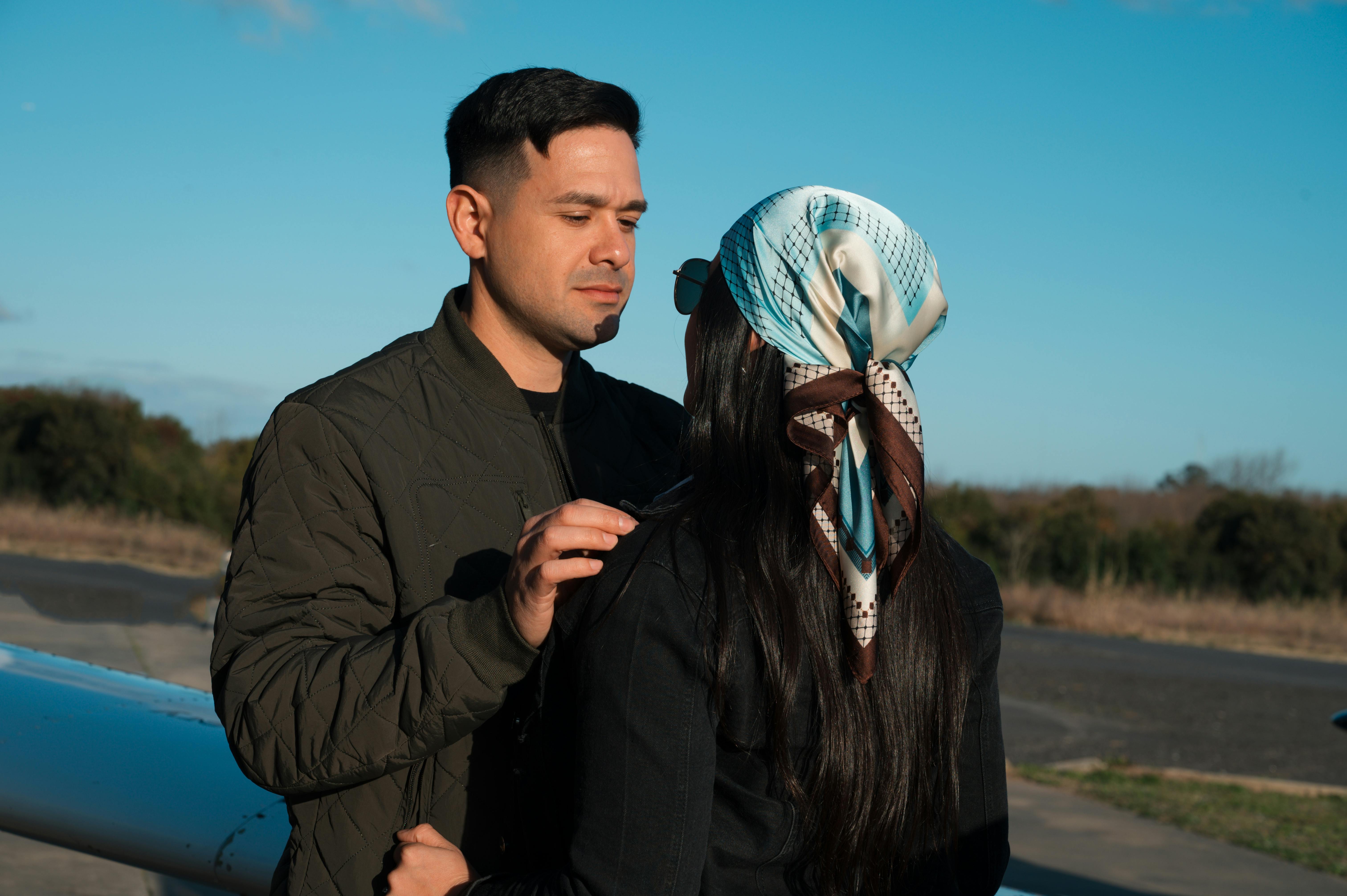 Zadarmo Pár sa dôverne rozpráva pri lietadle za slnečného dňa. Fotka z fotobanky