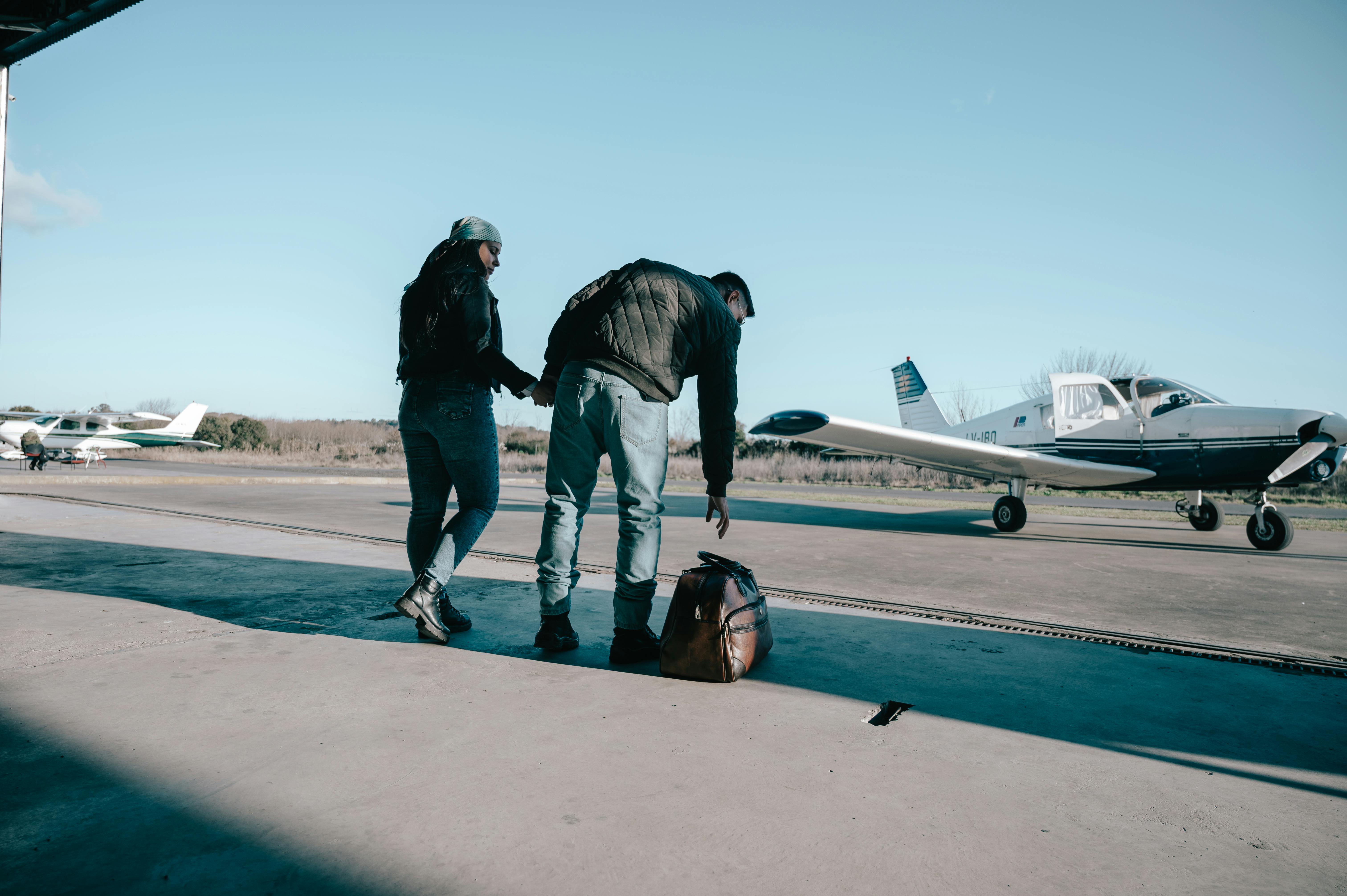 Zadarmo Dvaja ľudia sa pripravujú vedľa svojho malého lietadla vo vonkajšom hangári. Jasný slnečný deň. Fotka z fotobanky