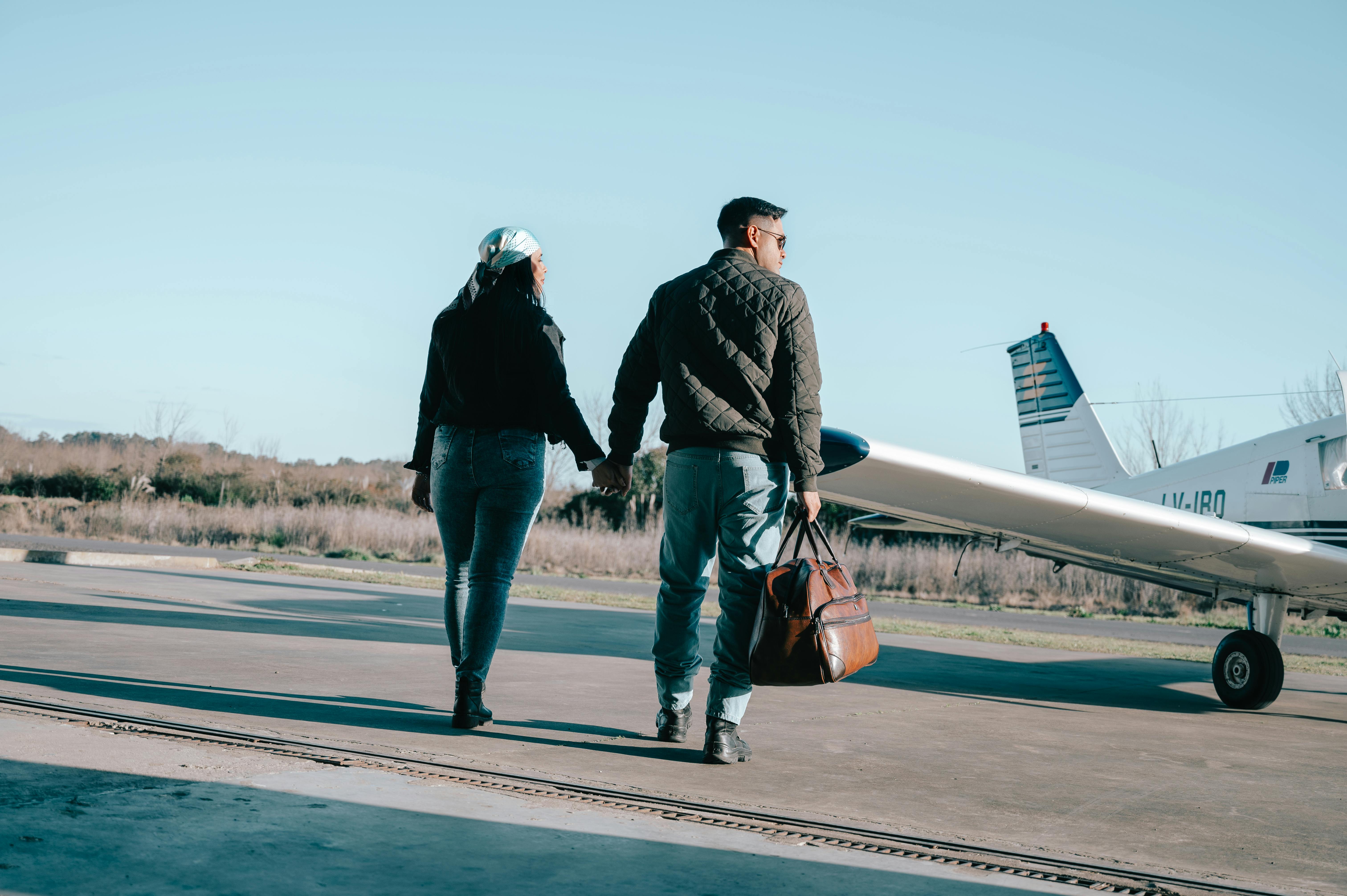 Zadarmo Muž a žena sa držia za ruky pri súkromnom lietadle za jasného jesenného dňa. Fotka z fotobanky