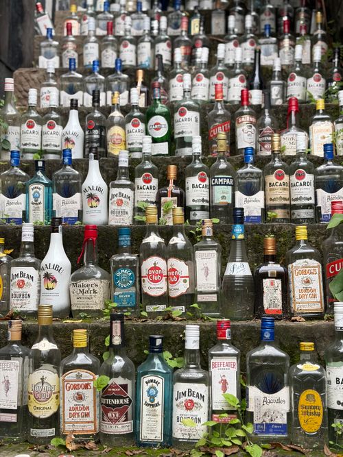 Free Vibrant arrangement of various empty liquor bottles on stone steps outdoors. Stock Photo
