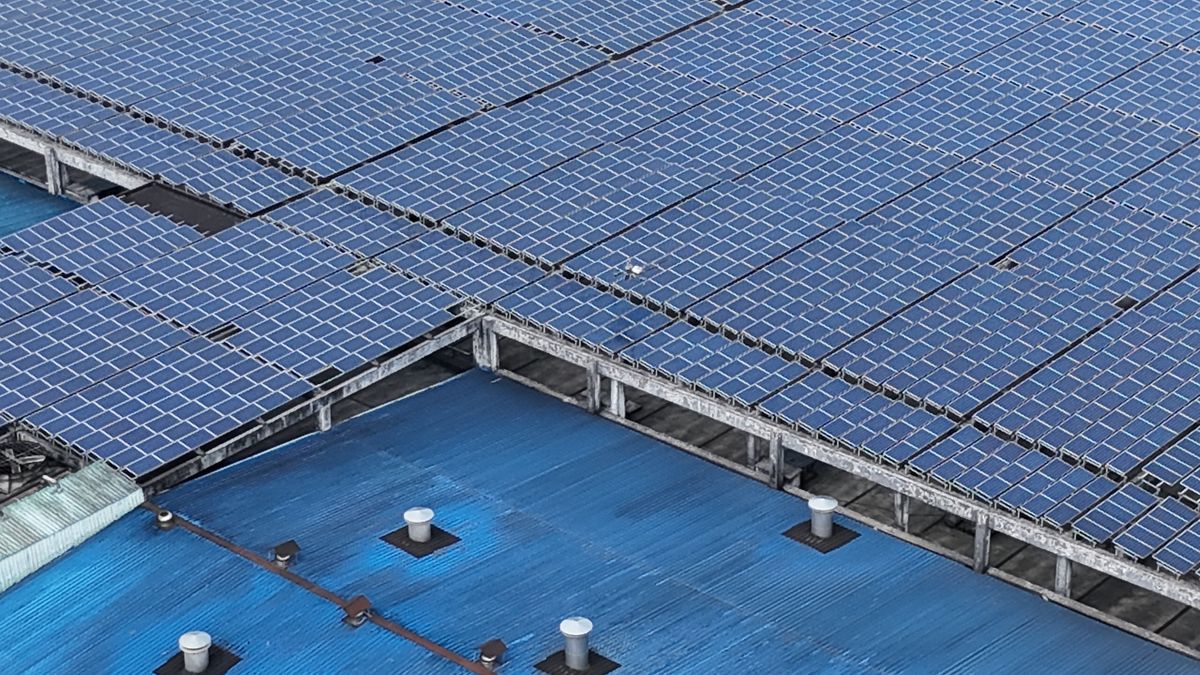 Aerial view of rooftop solar panels on industrial buildings, the typical generation source paired with a 3MWh containerized battery energy storage system