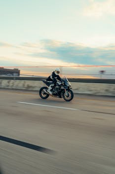 A biker speeds along a highway at sunset, showcasing exhilaration and freedom.