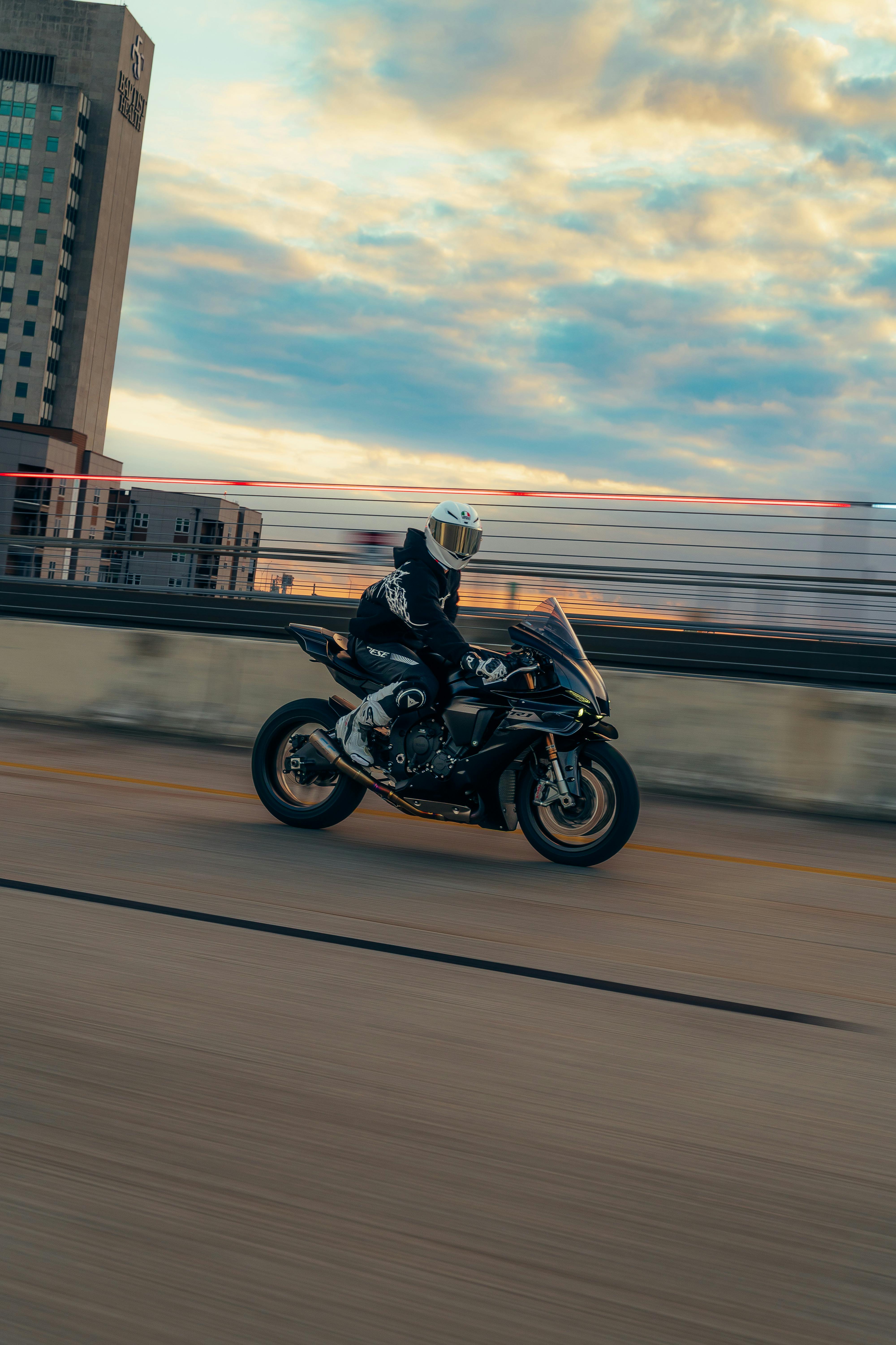 Kostenlos Wagemutiger Motorradfahrer in Aktion auf einer Stadtautobahn in der Abenddämmerung, der urbanes Abenteuer und Geschwindigkeit einfängt. Stock-Foto