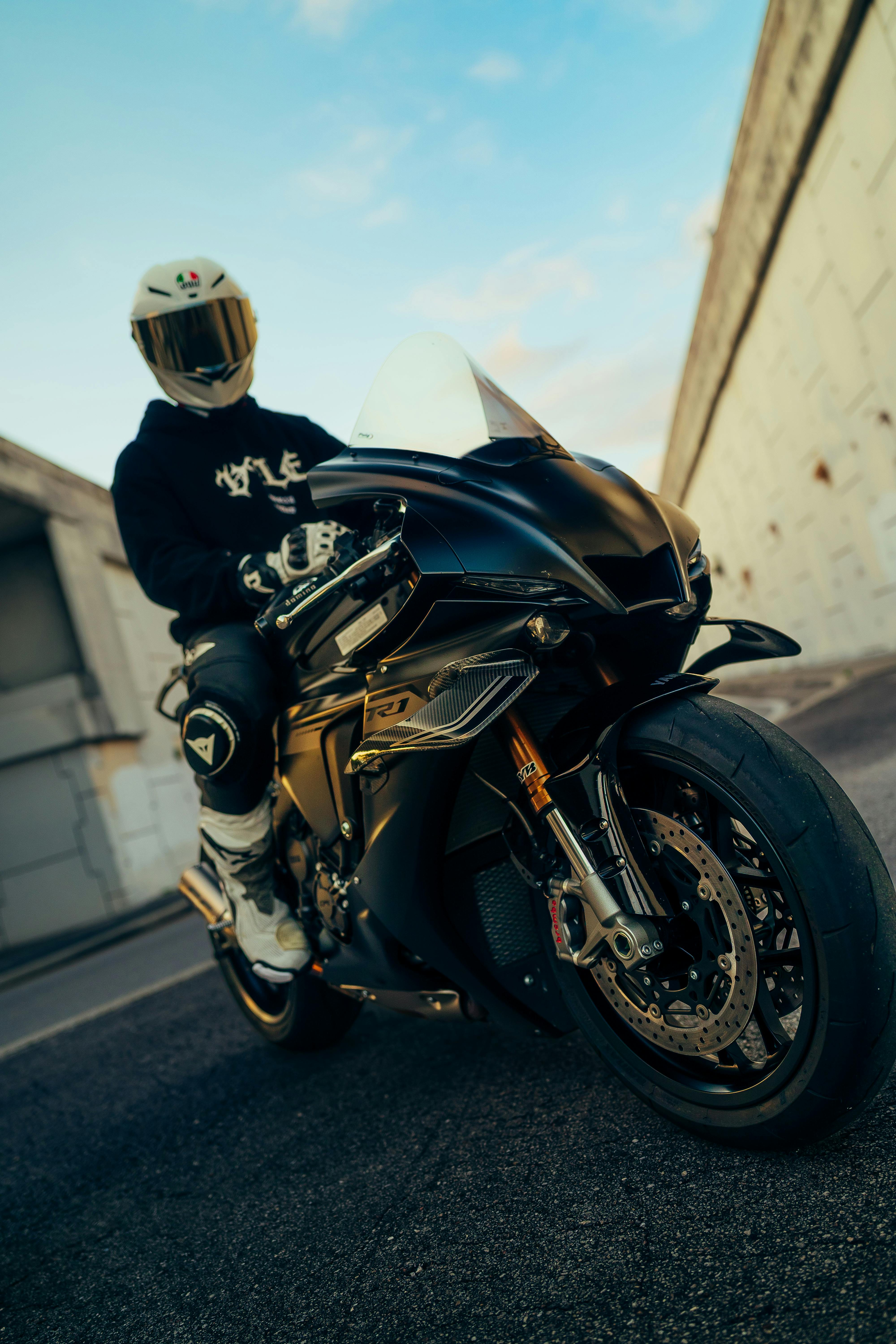 De franc Un motociclista genial amb equip de protecció i casc posa amb confiança en una elegant motocicleta esportiva negra. Foto d'estoc