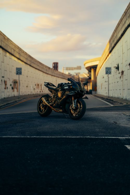 Free A powerful motorcycle parked on an urban street under the golden glow of sunset. Stock Photo