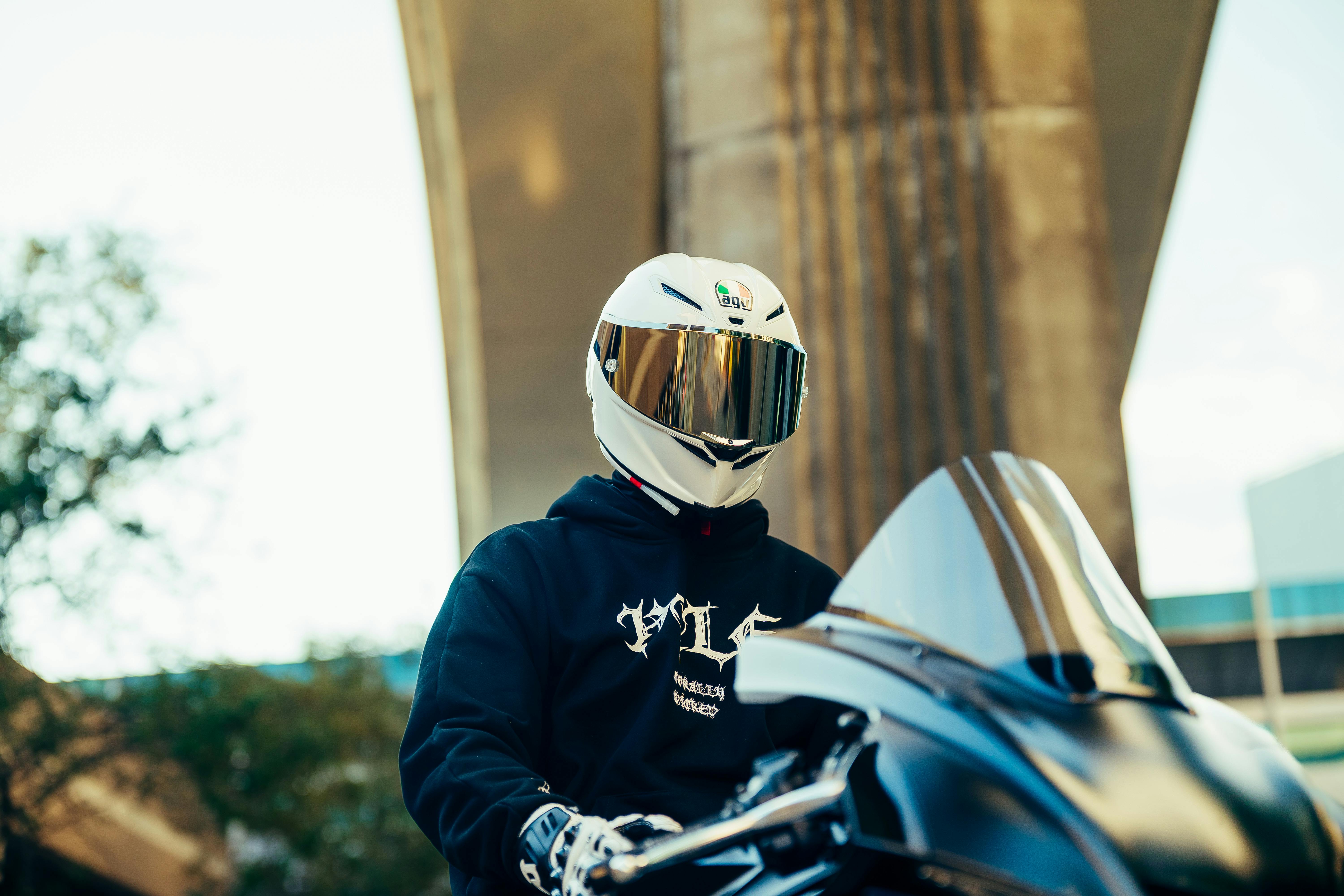 De franc Un motociclista amb un casc elegant es troba en un entorn urbà amb un toc modern. Foto d'estoc