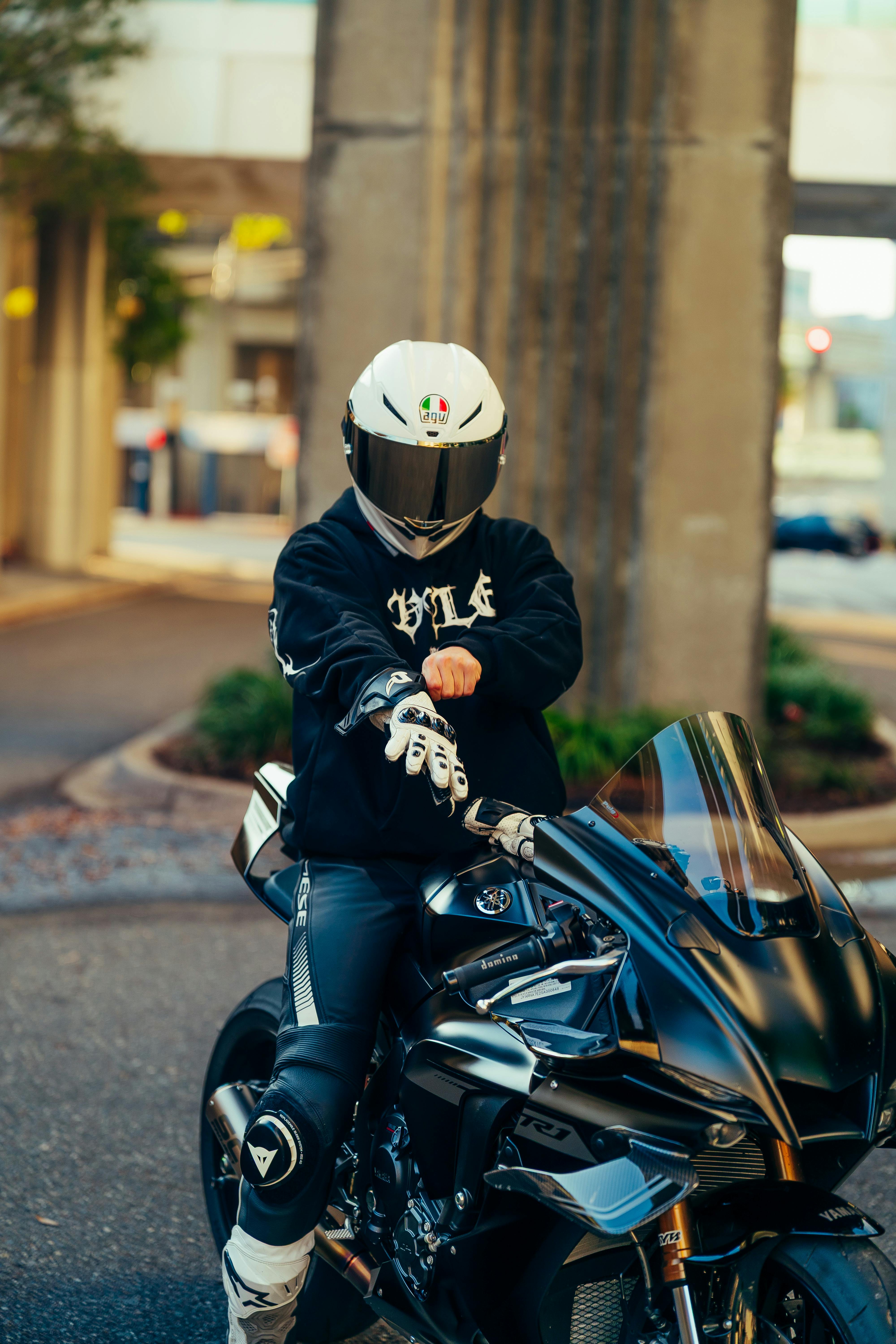 De franc Un pilot d'una motocicleta esportiva negra porta equip de protecció complet en un entorn urbà. Foto d'estoc