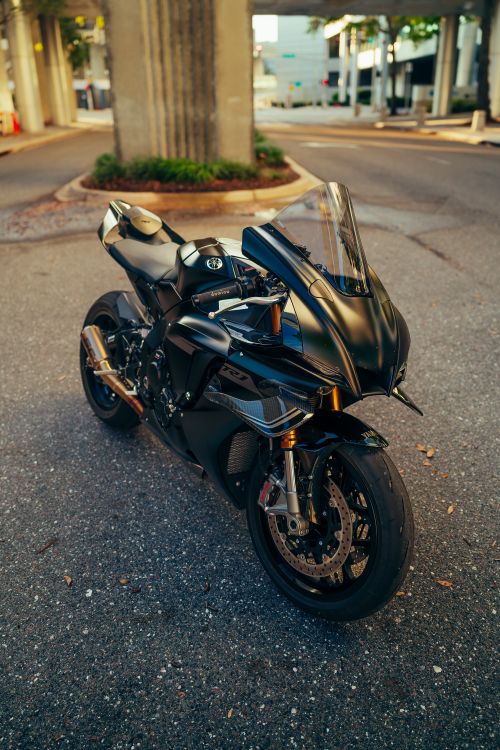 Free A black sport motorcycle parked on an empty street in a modern urban setting. Stock Photo