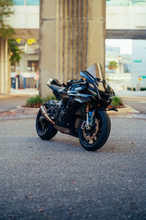 Free Black motorcycle in urban environment under a bridge with modern architecture. Stock Photo