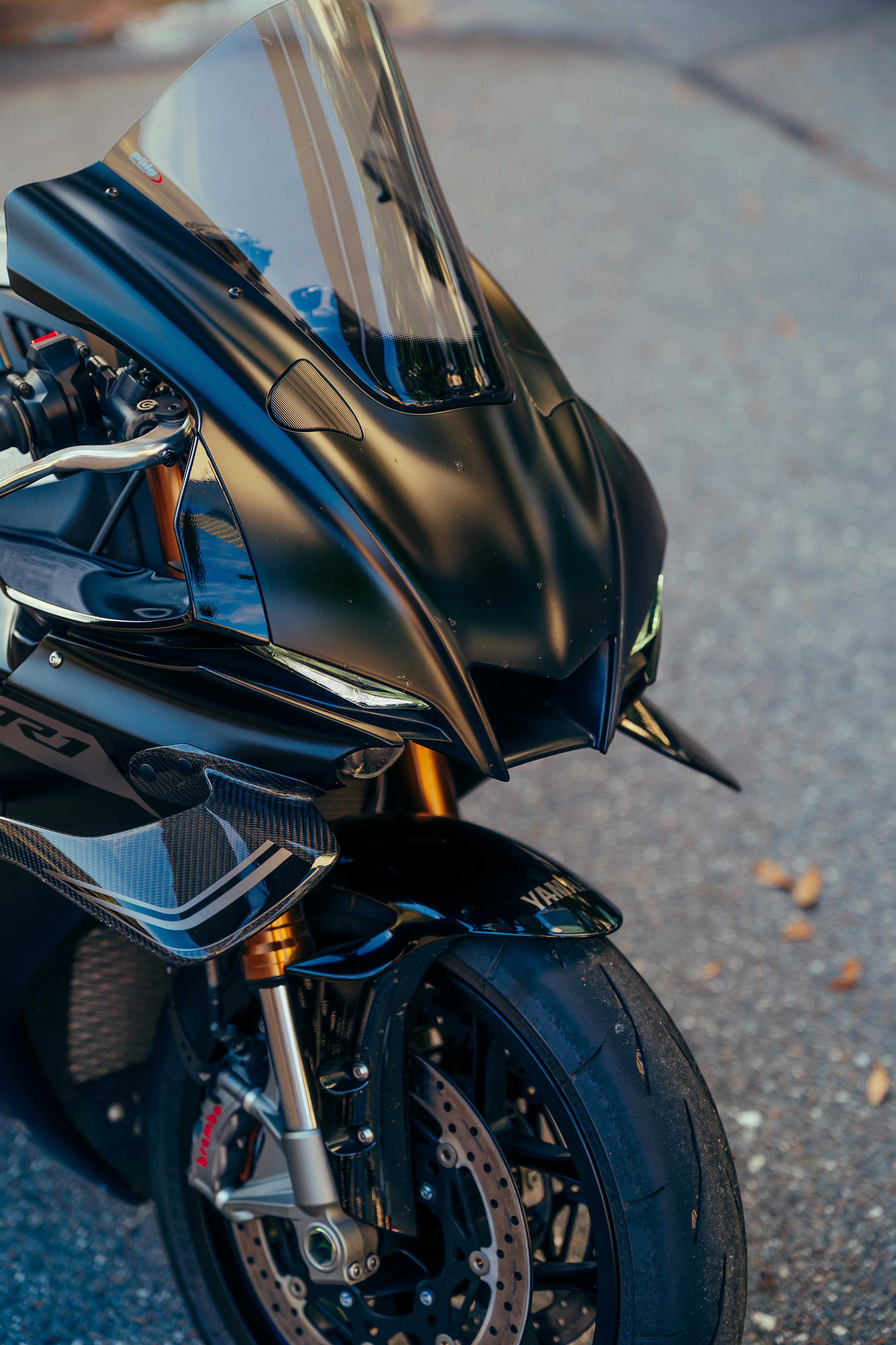 Kostenlos Nahaufnahme eines eleganten schwarzen Sportmotorrads, das im Freien geparkt ist. Stock-Foto