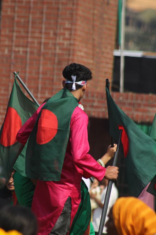 Free A man in traditional attire holds Bangladesh flag during a cultural event. Stock Photo