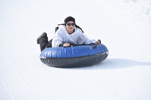 A woman having fun snow tubing down a snowy slope on a bright winter day.