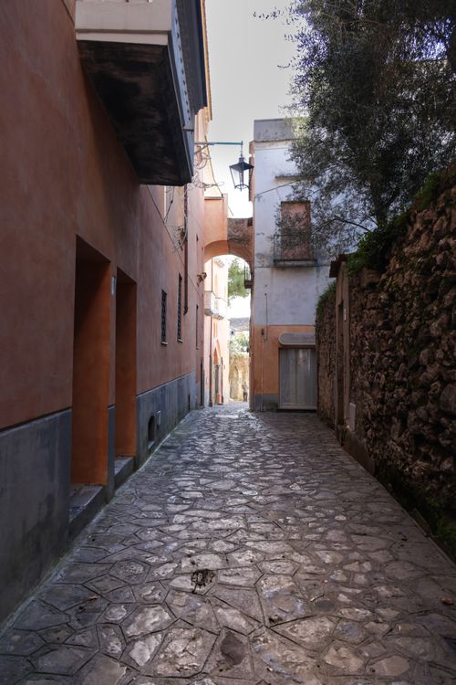 Free Discover a picturesque Italian alleyway with historic architecture and a rustic archway. Stock Photo