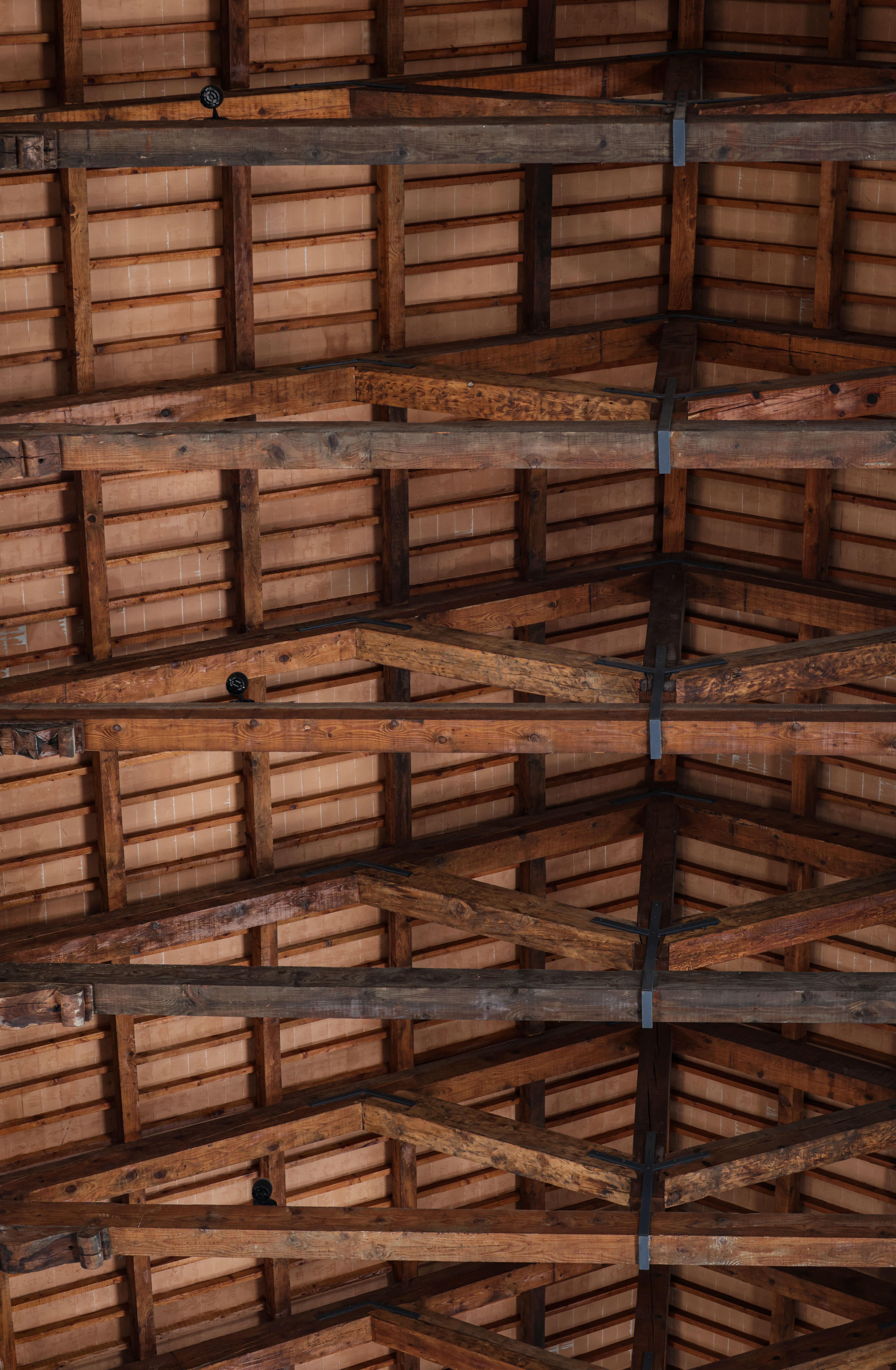Detailed view of a rustic wooden ceiling with exposed beams, highlighting natural textures.